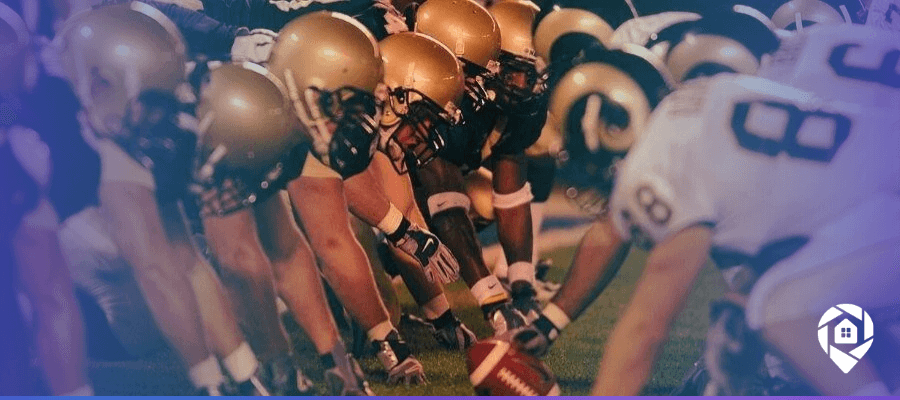 Football teams lined up at the line of scrimmage, ready for the snap during a game.