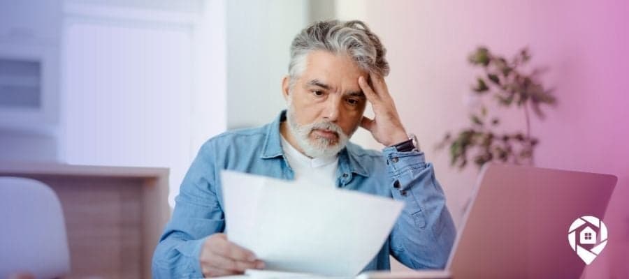 A man looking stressed at a paper to symbolize looking into back taxes on a property.