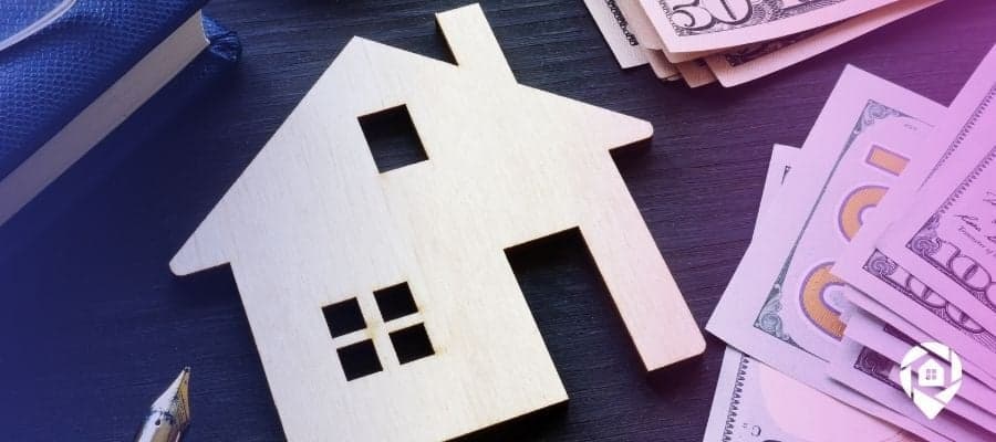 An image of a wooden house on a desk with a notebook and hundred and fifty dollar bills for the "Finding the Right Types of Real Estate Investments for You" blog header.
