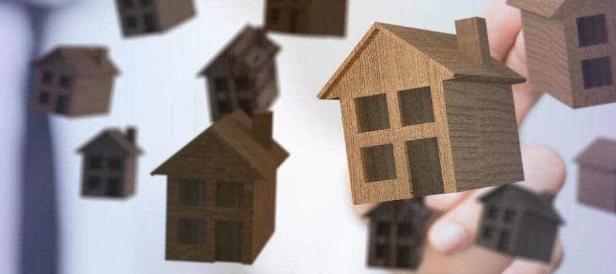 Floating wooden house models representing real estate investment opportunities.