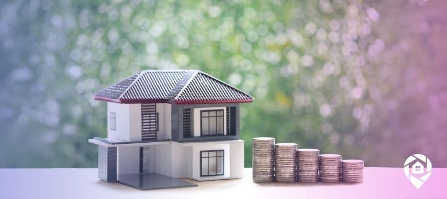 A small house on a table with decreasing stacks of coins to the right of it to symbolize the tips for real estate investing.