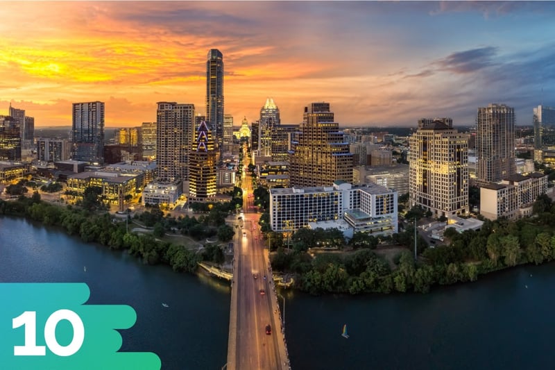 Aerial shot of road leading into downtown Austin, Texas with a few cars driving into the bustling downtown at sunset.