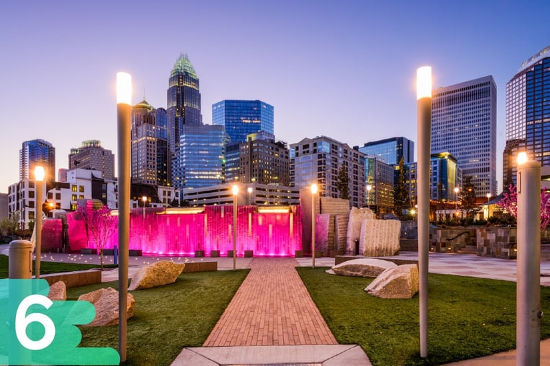 Downtown Charlotte, North Carolina in a park with rocks, grass, and monuments with a pink light on them.